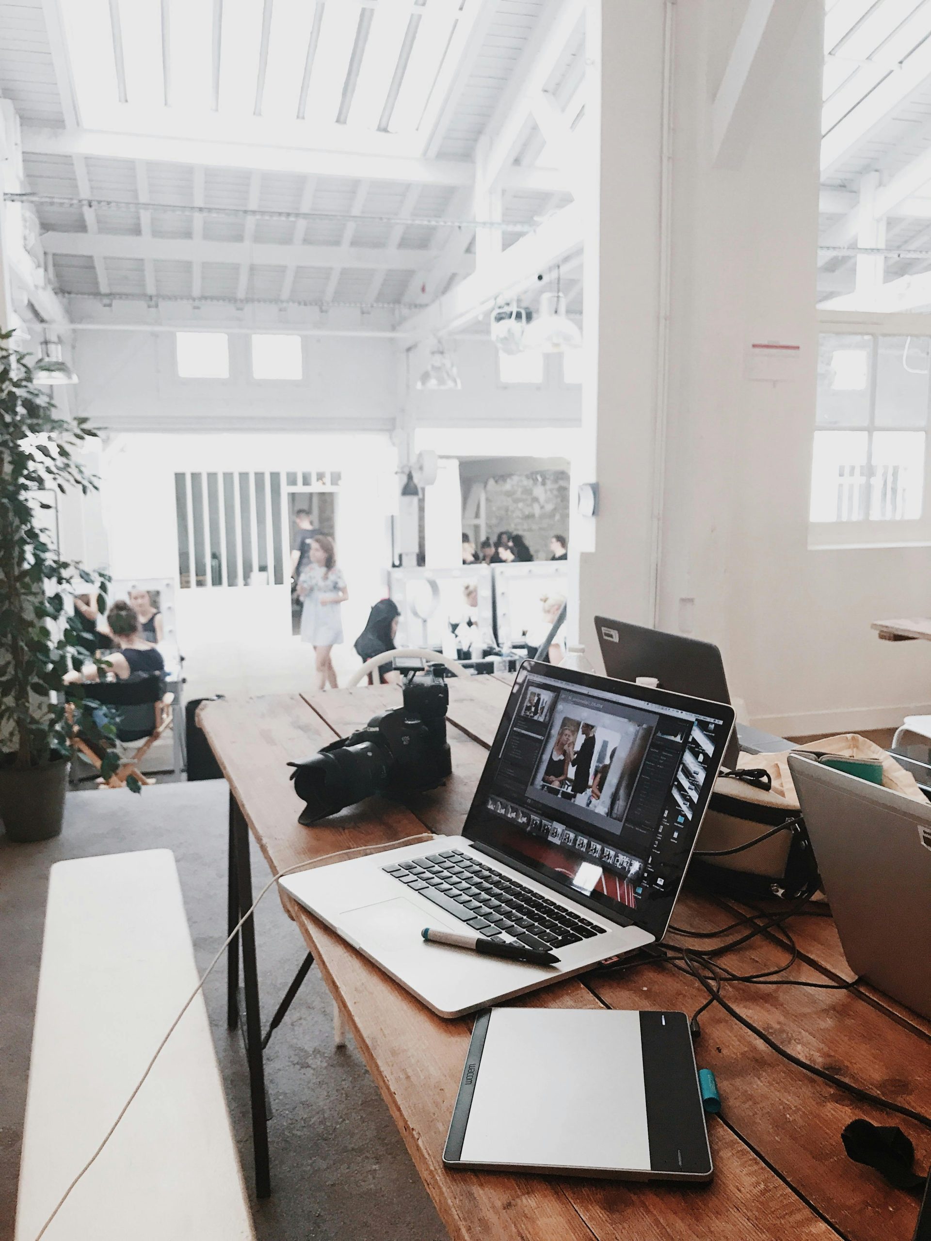 Coaching retour congé maternité A bright, modern workspace featuring laptops, a camera, and a drawing tablet in an indoor office.